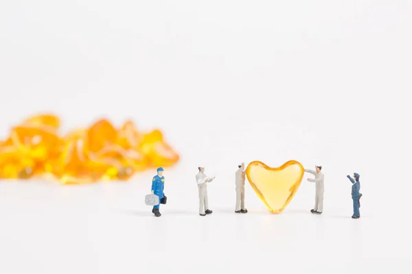 Personas en miniatura con aceite de hígado de bacalao sobre fondo blanco — Foto de Stock