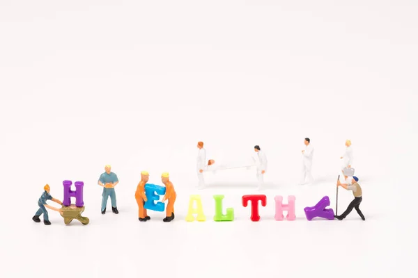 Κείμενο υγιή πολύχρωμη λέξη με μικροσκοπικά άτομα και την ομάδα υγείας — Φωτογραφία Αρχείου