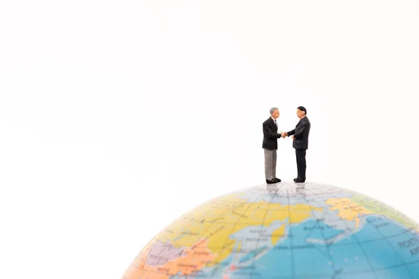 Business miniatura persone stretta di mano sul globo isolato su w — Foto Stock