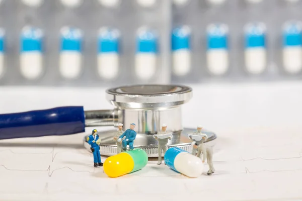 Pessoas em miniatura e drogas médicas com estetoscópio em branco, medi — Fotografia de Stock
