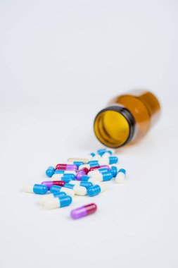 beyaz arka plan üzerinde şişeden düşen antibiyotik kapsülü
