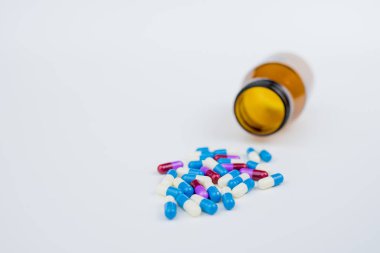beyaz arka plan üzerinde şişeden düşen antibiyotik kapsülü