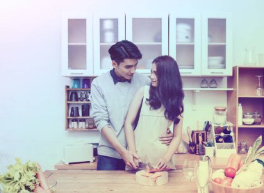 Asyalı çift mutfakta yemek pişiriyor. 