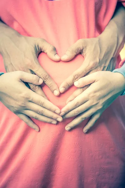 Embarazada y su marido sosteniendo sus manos en un grito de corazón — Foto de Stock