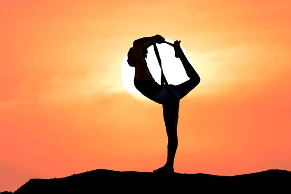 日没や日の出の背景を持つ女性の練習ヨガのシルエット — ストック写真