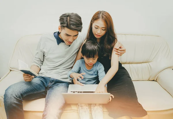 mutlu aile kanepede oturan ve lapto kullanmak için oğulları öğretim