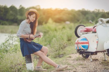 karayolu üzerinde ukulele ve klasik scooter oynayan turist