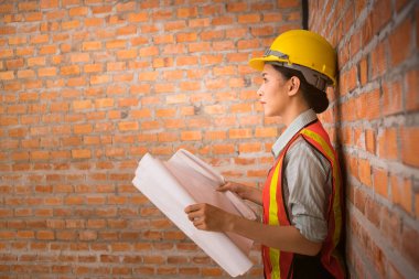 Tuğla duvar arka plan ile planları ile Asyalı mühendis kadın