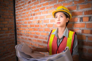 Tuğla duvar arka plan ile planları ile Asyalı mühendis kadın