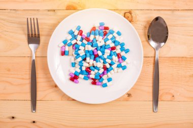 ahşap arka plan üzerinde beyaz plaka üzerinde ilaç kapsülü