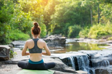 Asyalı genç kadın şelale yakınında yoga pratik