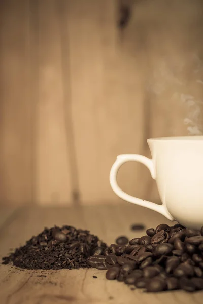 Xícara de café e grãos de café na mesa de madeira — Fotografia de Stock