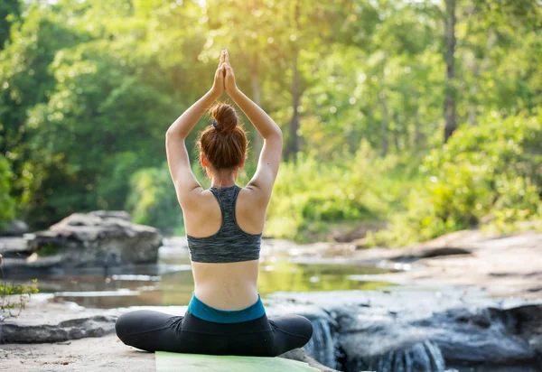 Asyalı genç kadın şelale yakınında yoga pratik