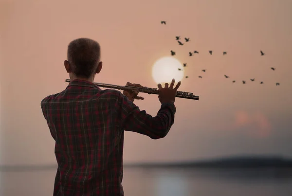 Hombre tocando la flauta con fondo al atardecer o al amanecer —  Fotos de Stock