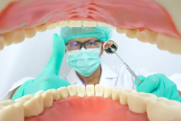 Стоматолог осмотрит полость рта с помощью стоматологического инструмента, зеркала и крючка — стоковое фото