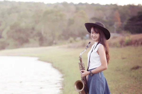 Woman with saxophone with nature background