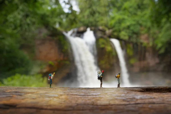 Mochileiro em miniatura com fundo cachoeira, conceito de turismo — Fotografia de Stock