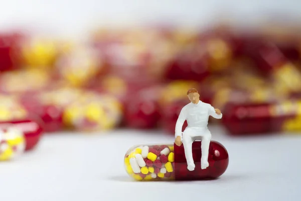 Miniaturowy osób z kapsułki medyczne narkotyków na białym tle — Zdjęcie stockowe
