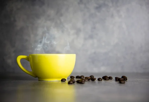 Tazza gialla di caffè e chicco di caffè con sfondo in cemento — Foto Stock