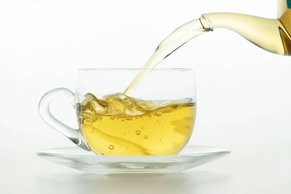 Chá derramando em xícara de chá no fundo branco — Fotografia de Stock