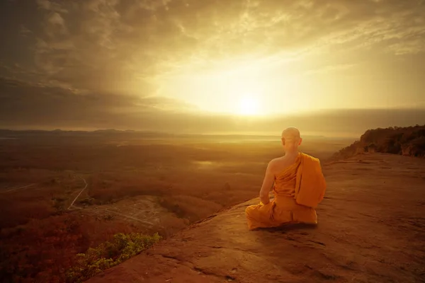 Buddhist monk in meditation at beautiful sunset or sunrise backg