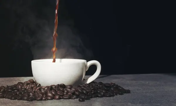 Coppa versando a tazza con chicco di caffè su sfondo nero — Foto Stock