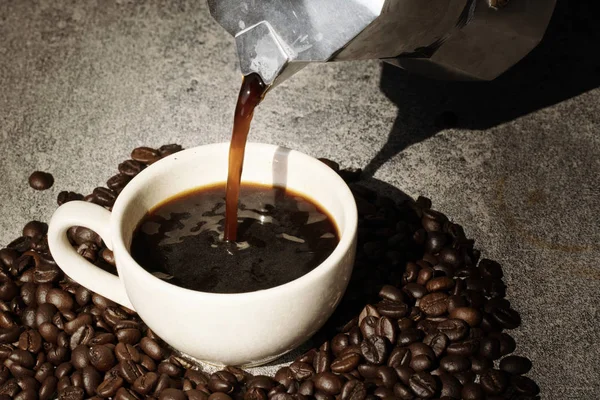 Caffè versando a tazza con chicco di caffè su sfondo nero — Foto Stock