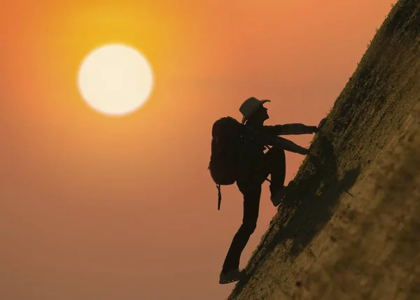 Silhouette of backpacker climbing on mountain at sunset or sunri