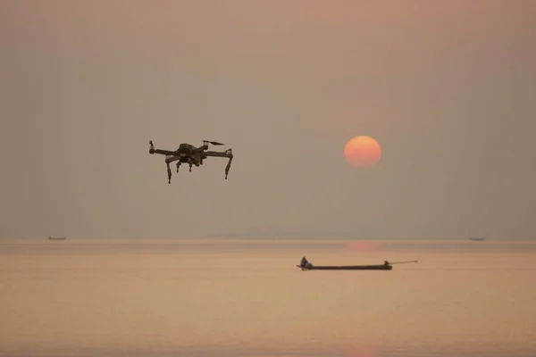 Flying drone on the sea with sunset background