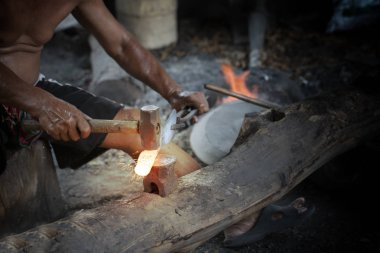 Demirci, örs üzerindeki erimiş metali elle dövmek
