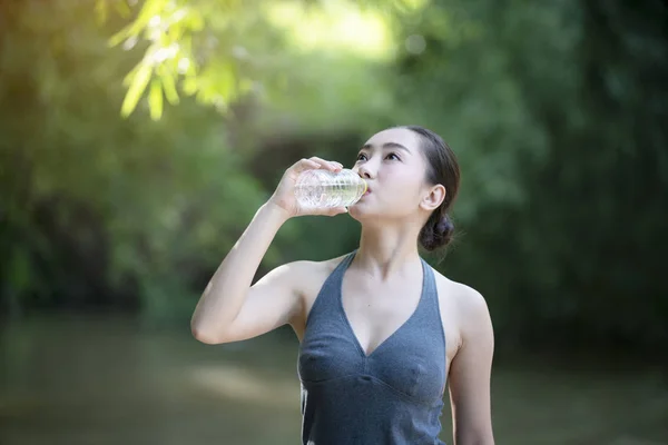 Donna che beve acqua dalla bottiglia in natura — Foto Stock