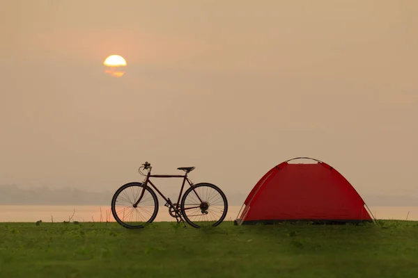 Tienda y bicicleta en el camping con puesta de sol o salida del sol backgrou — Foto de Stock