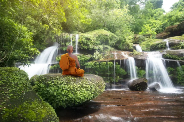 Buddha monk practice meditation at beautiful waterfall