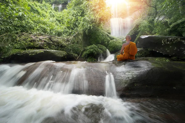Buddha monk practice meditation at beautiful waterfall