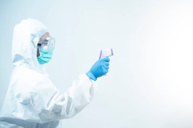 Kişisel koruma ekipmanı ya da PPE 'de çalışan bir doktor. dijital termometre, Coronavirus covid-19 salgın konsepti