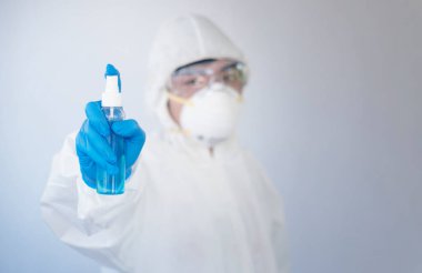 Kişisel koruma ekipmanı ya da PPE 'de çalışan bir doktor. Alkol spreyi şişesi, Coronavirus covid-19 salgın konsepti.