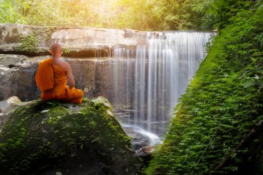 Buda keşişi şelaleyle meditasyon yapıyor.