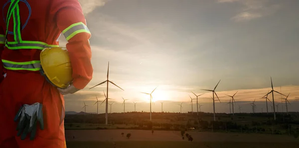 Rüzgar türbinli miğfer taşıyan mühendis gün batımında elektrik üretim silueti için tesis, temiz enerji konsepti