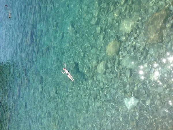 Vista aérea de una mujer delgada nadando en el mar turquesa transparente . — Foto de Stock