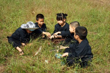 Ho Chi Minh City, Vietnam - 14 Ocak 2014: Grup, çocuklarda siyah geleneksel giysi, otlak üzerinde oturup birlikte, açık hava etkinliği Vietnamca yapmak çocuk, Vietnam için sağlıklı yaşam tarzı