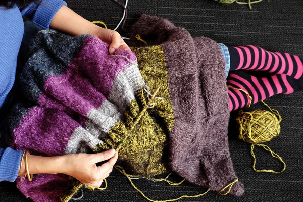 亚洲女人坐在家里的地板上 在冬天编织羊毛毯子取暖 编织是业余爱好的活动 制作手工制作的礼物 照片上的女人的手在一天的顶部看到 — 图库照片