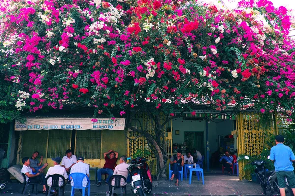 La gente se sienta bajo colorido enrejado de flores de buganvilla para el café —  Fotos de Stock