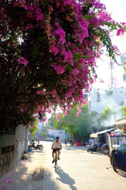 Adam begonviller çiçek altında sokakta bisiklete binmek
