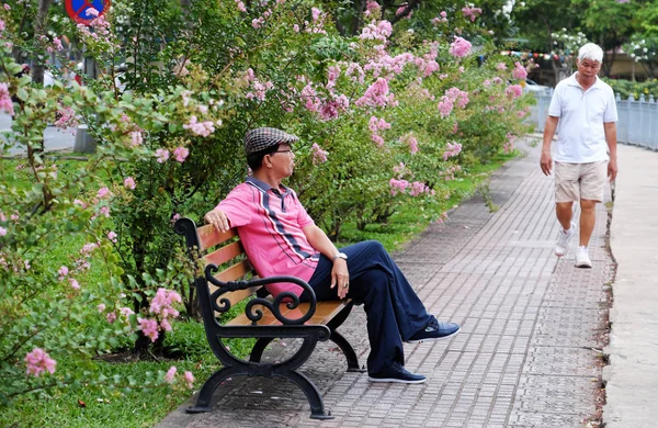 Hombre sentado en el banco, mientras que otro hombre caminando para hacer ejercicio — Foto de Stock