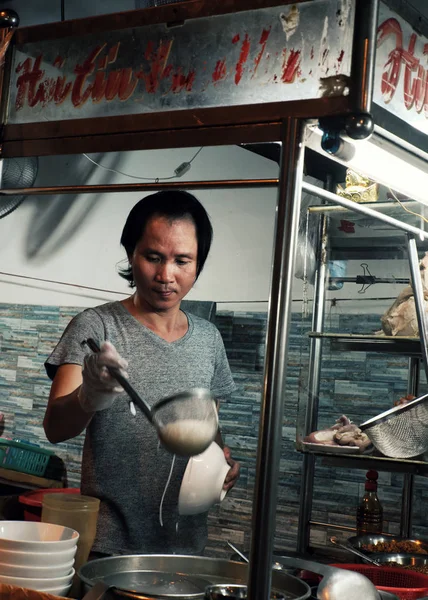 Вьетнамский продавец готовит суп с лапшой на тележке с едой на ночной улице — стоковое фото