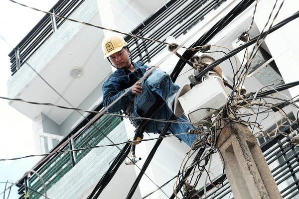 Vietnamský elektroenergetický pracovník šplhají vysoko na elektrickém postu — Stock fotografie