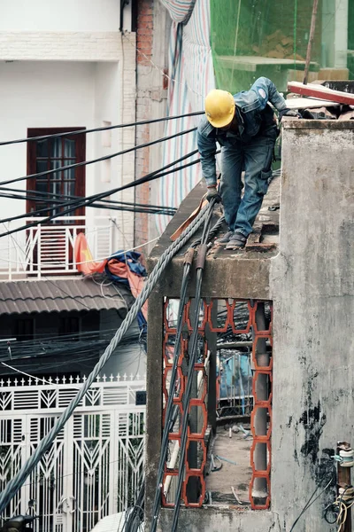 Trabalhador da eletricidade vietnamita subir alto no telhado da casa para reparar — Fotografia de Stock