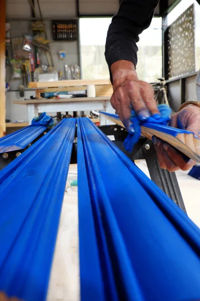 Pintura de manos masculinas en barra de madera con recubrimiento de pintura azul en varilla —  Fotos de Stock