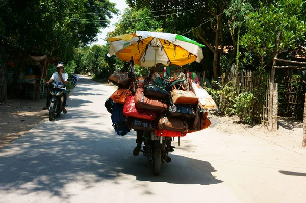 Vietnamese street vendor ride motorcycle, parasol hang handbag m — Stock Photo, Image