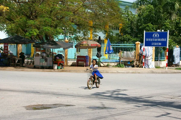 Vietnamese little girl riding bike cross road from school at noo — Stock Photo, Image
